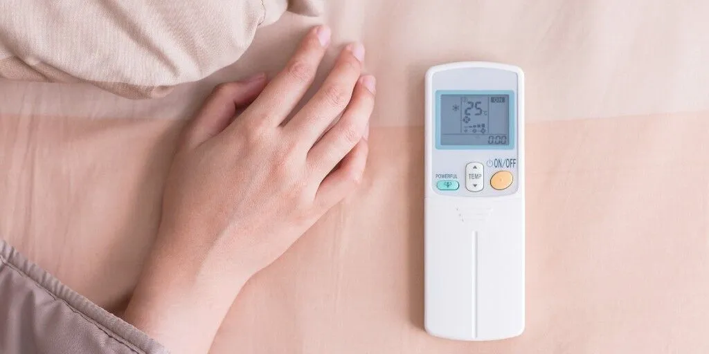 womans-hand-next-to-air-conditioning-remote