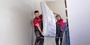 two-men-carrying-mattress-downstairs