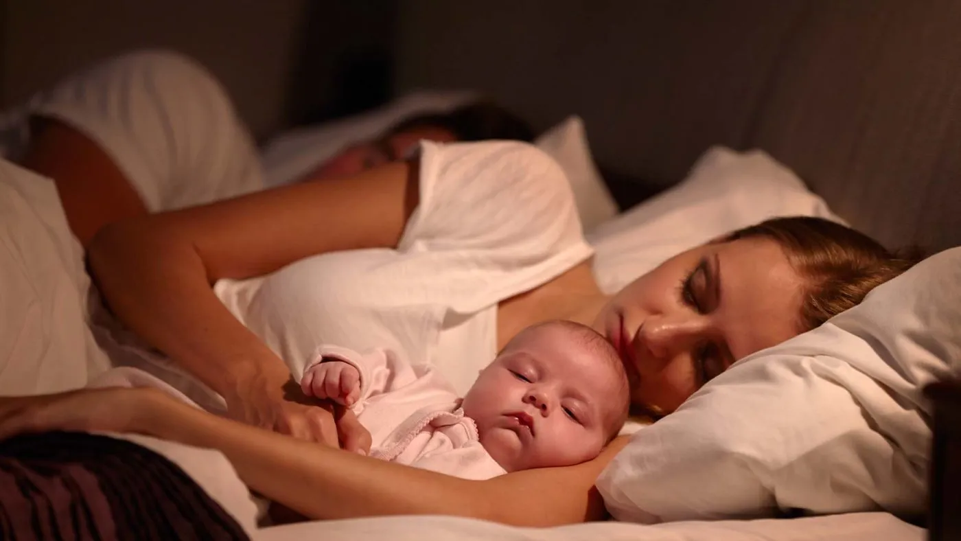 Mother sleeping with baby in a cozy bed